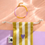 Ava&Yves - Perlenarmband lila/gelb mit Karabinerverschluss und Säckchen in ocker/weiss